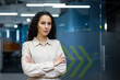 © Liubomir - Confident businesswoman standing with arms crossed in modern office. Professional attire, modern workplace, and determined expression convey leadership, confidence, and professionalism.