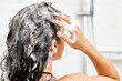 © producer - Young woman taking refreshing shower in white modern bathroom. Girl washing her hair, back view