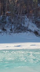 Fototapete - Vertical aerial video of thaw on the river Katun with banks covered by ice and snow in winter season.
