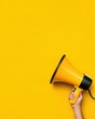 © ParinApril - A vibrant yellow megaphone held against a bright yellow background, symbolizing communication and attention-grabbing messages.