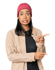 Wall Mural - young filipino woman in studio shocked pointing with index fingers to a copy space.