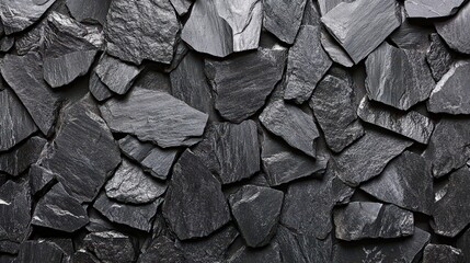 Poster - A unique wall composed of dark slate stones arranged in an irregular pattern, showcasing various shapes and textures