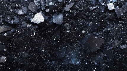 detailed arrangement of black ice fragments scattered against a dark background, with shimmering spo