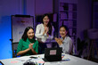 © Parichat - Group of Young Professionals Celebrating Success During a Late-Night Office Meeting with Laptops and Charts