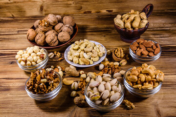 Poster - Various nuts (almond, cashew, hazelnut, pistachio, walnut) in bowls on a wooden table. Vegetarian meal. Healthy eating concept