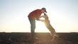© maxximmm - Farmer and his dog play together in field. farming is the concept of caring for pet. a man and his dog are in friendship together. a man and a dog playing together in a field lifestyle.