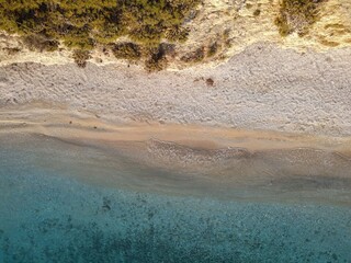 Sticker - Aerial view of a serene beach with clear blue water and sandy shore