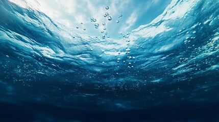 Beautiful underwater scene capturing bubbles rising through a clear blue ocean surface.