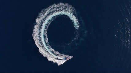 Wall Mural - aerial top view of a motor rib boat forming a circle of waves and bubbles with its engine over the b