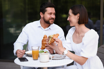 Wall Mural - Happy couple having breakfast in outdoor cafe