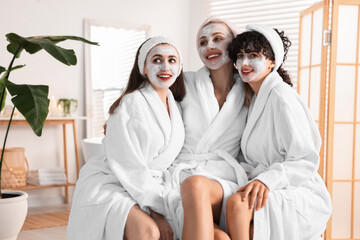 Wall Mural - Happy friends in bathrobes with facial masks indoors. Spa party