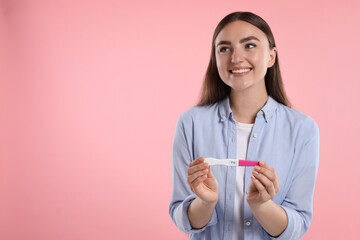 Sticker - Happy woman holding pregnancy test on pink background, space for text