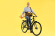 © New Africa - Happy postman on bicycle delivering letters against yellow background