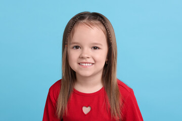 Wall Mural - Portrait of happy little girl on light blue background