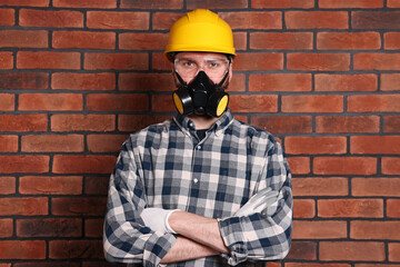 Wall Mural - Man in respirator mask and hard hat near red brick wall