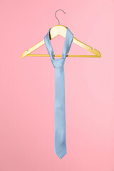 Poster - Hanger with light blue tie on pink background