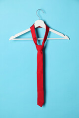 Wall Mural - Hanger with red tie on light blue background