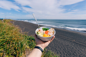 Wall Mural - Food Fresh poke with salmon and crab against the backdrop of black ocean beach.