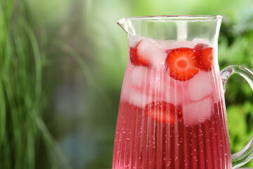 Wall Mural - Freshly made strawberry lemonade in jug outdoors, closeup. Space for text