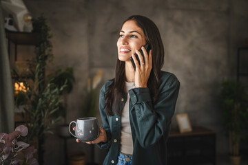 Portrait of adult young woman stand hold cup and talk on mobile phone