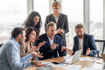 Aufkleber - A group of business professionals gather around a laptop in a modern office setting, displaying excited reactions to the information on the screen. They are gathered around a large wooden table