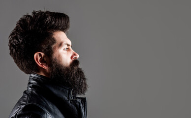 Sticker - Male model with stylish hair, beard. Serious man with long beard and mustache. Barber fashion and beauty. Bearded man with stylish hairstyle in black leather jacket. Copy space barbershop advertising.