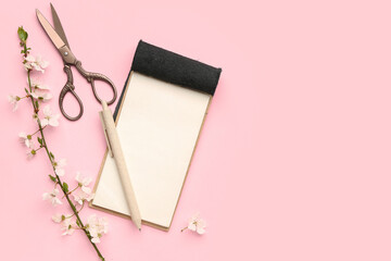 Wall Mural - Composition with blooming tree branch, notebook, pencil and scissors on pink background