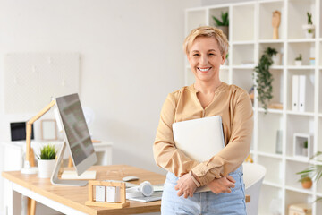 Mature female programmer with laptop in office