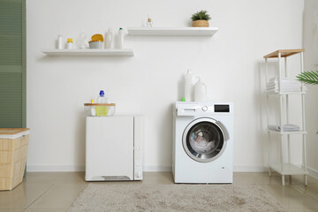 Poster - Interior of modern laundry room with washing machine, bottles of laundry detergent and towels on shelving unit