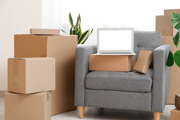 Wall Mural - Blank laptop with moving boxes on armchair and plants near window in room