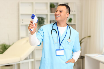 Poster - Handsome doctor with infrared thermometer in clinic