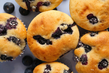 Tasty blueberry muffins on light background, closeup