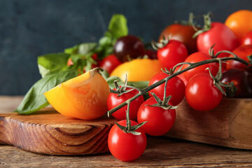 Tomatoes on board on wooden table against black background. Closeup