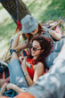 © qunica.com - Two young friends relax on a hammock in the park, sharing laughter and bonding under the warm sun on a bright day.
