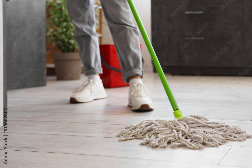 Young woman mopping floor in kitchen, closeup