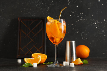 Wall Mural - Glass of Aperol spritz cocktail with fruits and sugar on black background