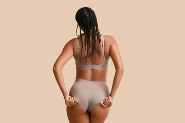 Wall Mural - Young woman in underwear on beige background, back view