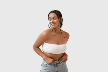 Wall Mural - Young African-American woman in bra on white background