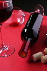 Canvas Print - Bottle of wine, glasses and corks on red table, closeup