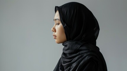 Islamic female model wearing hijab on blank background from side view