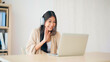 © Monster Ztudio - Young asian woman wearing headset while working on computer laptop at house. Work at home, Video conference, Video call, Student learning online class