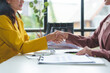 © Phimwilai - Businesswoman and financial representative shake hands after agreeing on a budget for business expansion and investment. Plans for construction projects Real estate finance concepts.