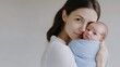 © The Little Hut - A mother holding her newborn baby over her shoulder both wrapped in soft blue and white clothing as the baby looks alert and curious in a loving and tender moment : Generative AI
