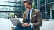 © Borneo - Smiling mature successful businessman working, typing on laptop sitting outdoors at office building