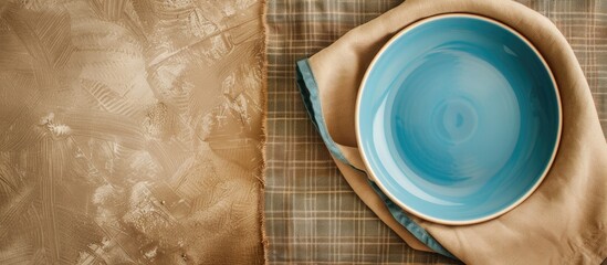 Wall Mural - Top view of an empty blue plate on a tablecloth with a napkin and copy space image for your design