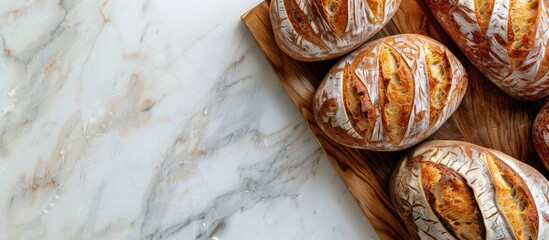 Poster - A high quality photo of a bakery display featuring golden rustic loaves of bread on a wooden board placed on a light background captured from above with a layout including copy space image