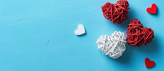 Leinwandbilder - Valentine s Day themed flat lay featuring white rattan hearts with a red heart on a blue background ideal for a greeting card with copy space image