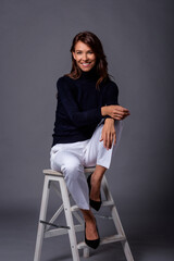 Wall Mural - Full length studio shot of a mid aged woman sitting against isolated background