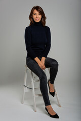 Sticker - Full length studio shot of a mid aged woman sitting against isolated background