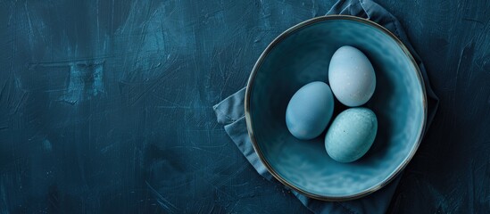 Aufkleber - A flat lay photo featuring three blue Easter eggs in a ceramic bowl on a dark blue backdrop with selective focus offering copy space image